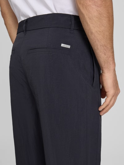 Mannenmodel draagt Hose mit Gesäßtaschen und Label-Detail van ARMANI EXCHANGE in donkerblauw, regular fit, steekzakken, achterzakken, labeldetail, bandwijdte maat 32: 44 cm, binnenbeenlengte maat 32: 79 cm, detailopname rugzijde.