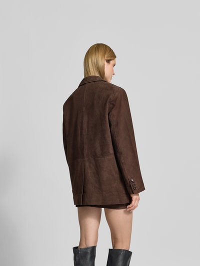 Frauenmodel trägt Blazer aus echtem Ziegenvelours von ROTATE in Dunkelbraun mit Reverskragen und Pattentaschen, Oversized Fit, Ganzkörperansicht Rückansicht.