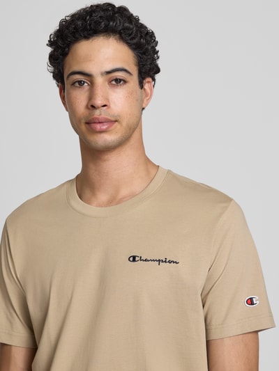 Männermodel trägt T-Shirt mit Logo-Stitchings Modell 'ICONS CONTRAST' von CHAMPION in Beige, Baumwoll-Mix, Nahaufnahme Oberkörper.