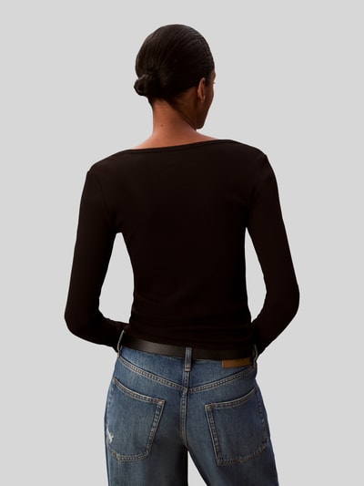 Vrouwenmodel draagt Gürtel aus echtem Leder Modell 'ESSENTIAL EFFORTLESS 3.0' van Tommy Hilfiger, zwart glad leer met metalen logo, unicolor, gedragen met jeans, productcontext: damesriem van echt leer met doornsluiting en merkapplicatie, volledig zicht van achteren.