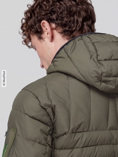 Mężczyzna nosi kurtkę pikowaną z kapturem Regular Fit model 'OW_Urbanex' od BOSS Green w kolorze oliwkowym, tekstura matowa, detailaufnahme pleców, KI-modifiziertes Bild.