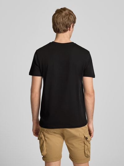 Männermodel trägt T-Shirt mit Logo und Rundhalsausschnitt von Alpha Industries aus Reiner Baumwolle im Regular-Fit, schwarze Farbe, Rückenlänge bei Größe M 67 cm, Ganzkörperansicht Rückansicht.