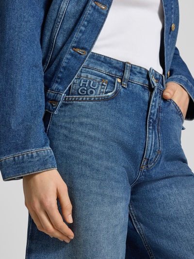 Frauenmodel trägt Regular Fit Wide Leg Jeans aus reiner Baumwolle Modell 'Geredith' von HUGO in Blau mit Label-Patch, 5-Pocket-Design, Nahaufnahme Oberkörper.