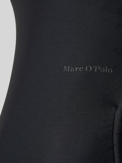Frauenmodel trägt Badeanzug mit Label-Schriftzug Modell 'ABSTRACT FLORAL' von Marc O'Polo, Optik: Unifarben, Materialverarbeitung: Stretch, Nahaufnahme Oberkörper.