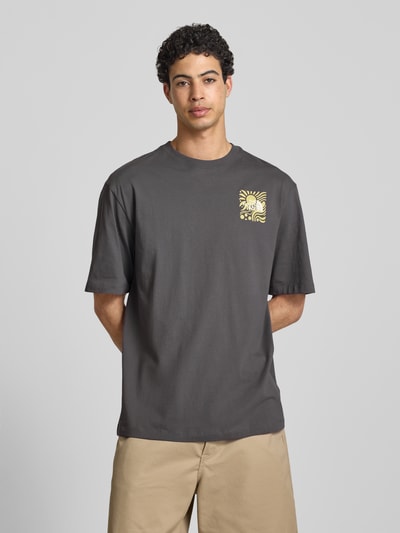 Männermodel trägt Oversized T-Shirt mit Logo-Print von The North Face in Dunkelgrau, reine Baumwolle, lockerer Schnitt, Ganzkörperansicht von vorne.