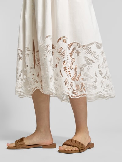 Frauenmodel trägt Midikleid mit Loch-Stickerei Modell 'Cecily' von SUNCOO PARIS, reine Baumwolle, weiße Farbe, Detailaufnahme Beine.