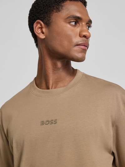 Männermodel trägt Relaxed Fit T-Shirt aus reiner Baumwolle Modell 'TEE 10' von BOSS für BOSS Green, beige, glatter Stoff, Nahaufnahme Oberkörper