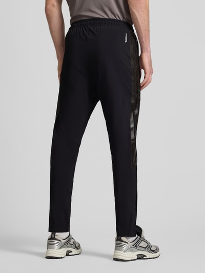 Männermodel trägt Sweatpants mit elastischem Bund von adidas Sportswear, Material-Mix mit Stretch-Anteil, Lockerer-Schnitt, schwarze Farbe, französische Eingrifftaschen, Tunnelzug, Innenbeinlänge bei Größe M 71 cm, Ganzkörperansicht Rückansicht.