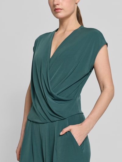Modelka kobieca nosi Jumpsuit in Wickel-Optik mit V-Ausschnitt od ROBE LÉGÈRE, zielony, materiał z dodatkiem stretchu, krój regular fit, szerokość w rozmiarze 36: 42 cm, długość całkowita: 147 cm, długość nogawki: 63 cm, widoczne detale na górze, zbliżenie na górną część ciała.