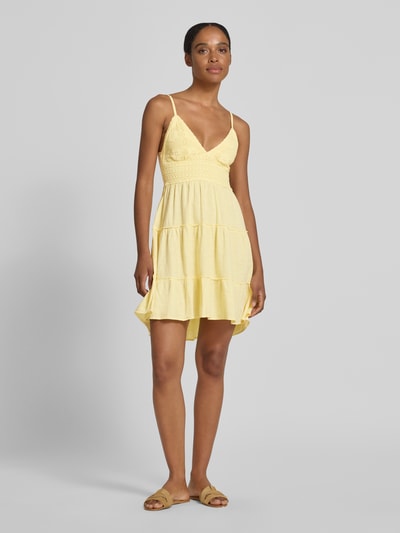 Frauenmodel trägt Minikleid mit rückseitigem Cut Out von Apricot in Gelb aus Reine Baumwolle mit Häkelspitze, Taillierter Schnitt, V-Ausschnitt und Spaghettiträgern, Ganzkörperansicht von vorne.
