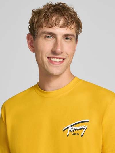Männermodel trägt gelbes Regular Fit T-Shirt aus reiner Baumwolle von Tommy Jeans, glatte Textur, Nahaufnahme Oberkörper, Herren T-Shirt von Tommy Jeans.