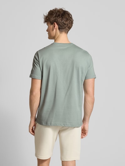 Męski model nosi T-Shirt mit Label-Print und Rundhalsausschnitt od CHAMPION, czysta bawełna, krój regular fit, długość tyłu w rozmiarze M: 69 cm, widok całej sylwetki od tyłu.