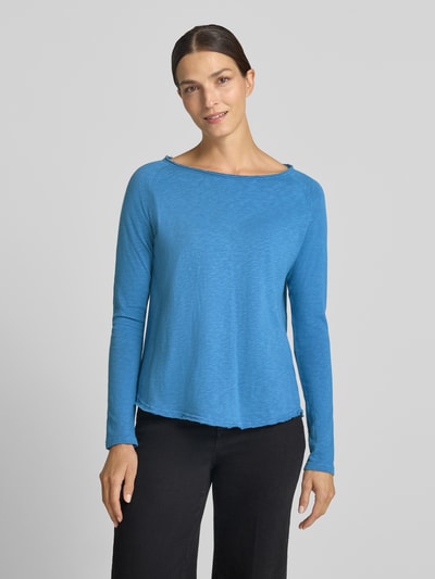 Frauenmodel trägt Regular Fit Longsleeve aus reiner Baumwolle von Rich & Royal in Blau, U-Boot-Ausschnitt, offene Säume, Ganzkörperansicht von vorne.