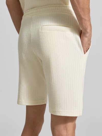 Männermodel trägt Regular Fit Shorts mit Tunnelzug van MCNEAL in crème katoenmix met stretch, steekzakken, achterzak, binnenbeenlengte 23 cm, bandwijdte maat M 43 cm, textuur met fijne ribstructuur. Ganzkörperansicht Rückansicht.
