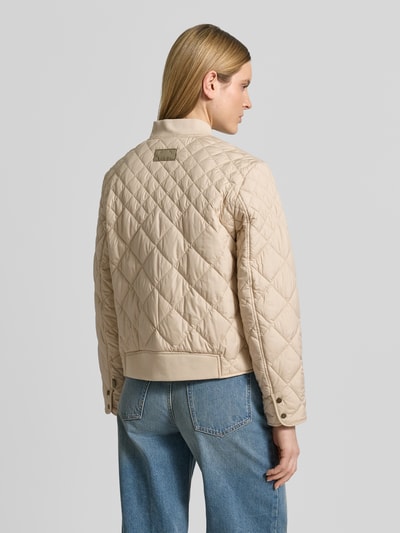 Frauenmodel trägt Steppjacke mit Eingrifftaschen von Fuchs Schmitt in Beige, Stehkragen, gerade Form, gesteppt, Ganzkörperansicht Rückansicht.