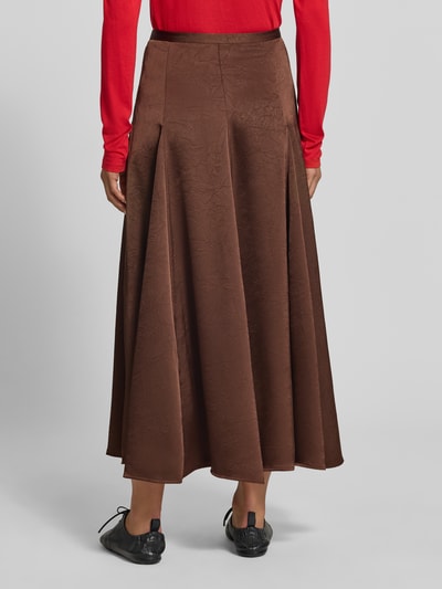 Frauenmodel trägt Maxirock mit Strukturmuster von MYON in Braun, leichte A-Linie, Satin, Produktdetails laut Kontext, Ganzkörperansicht Rückansicht.