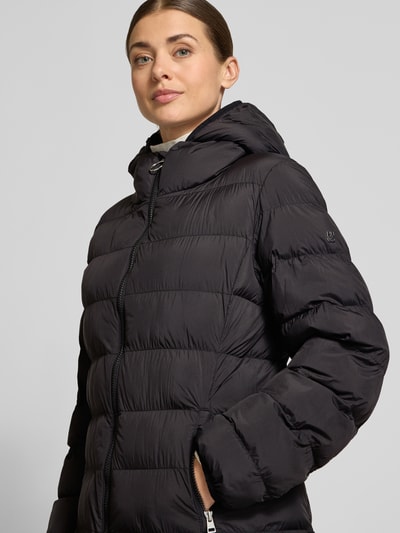 Frauenmodel trägt Regular Fit Steppmantel mit Kapuze Modell 'Famalia-4' von HUGO in Unifarbe matt mit Reißverschlusstaschen, Nahaufnahme Oberkörper.