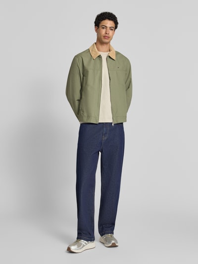 Męski model nosi Regular Fit Blouson aus reiner Baumwolle von Tommy Jeans, efekt: jednolity kolor, krój regular fit, wykładany kołnierz, zamek błyskawiczny, wyhaftowane logo, pas na plecach, patki, długi rękaw, mankiet, patka na dole, boczne wpuszczane kieszenie, wykończenie materiału: cieniowana przędza, materiał: bawełna; pełny widok od przodu.