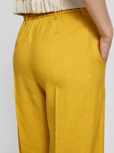 Frauenmodel trägt Wide Leg Hose aus Leinen-Mix von Windsor in Gelb, spürbare Textur, sichtbare Bügelfalten, Nahaufnahme Rückansicht. Bundweite 38 cm, Innenbeinlänge 67 cm, Lyocell-Anteil, elastischer Bund.