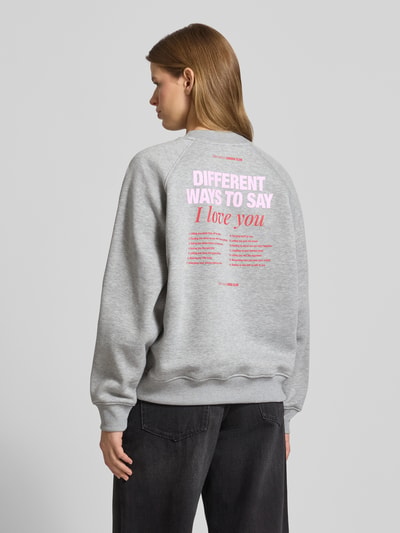 Frauenmodel trägt Sweatshirt mit Label-Print Modell 'Loretta' von LeGer by Lena Gercke in Grau mit rosafarbenem Text, Baumwoll-Mix, Loose Fit, gerippte Abschlüsse, Ganzkörperansicht Rückansicht.