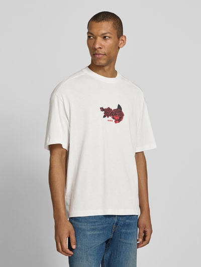 Männermodel trägt Oversized T-Shirt aus reiner Baumwolle Modell 'DOMANS' von HUGO in Weiß mit Fotoprint, Rundhalsausschnitt, Ganzkörperansicht von vorne.