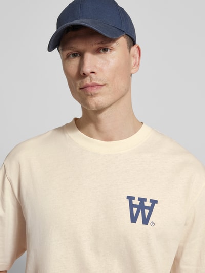 Męski model nosi Relaxed Fit T-Shirt mit Logo-Print Modell 'Liam' od Wood Wood, bawełna, okrągły dekolt, kontekst marki, zbliżenie na górną część ciała