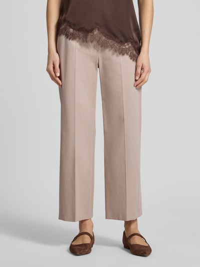 Frauenmodel trägt Slim Fit Hose mit Bügelfalten von Windsor, beigefarbener Baumwoll-Elasthan-Mix, mit Gesäßtaschen, Ganzkörperansicht von vorne.