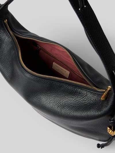 Produktfoto, schwarze Shoulder Bag mit Logo-Print Modell 'Thess' von Coccinelle, goldener Reißverschluss, strukturierte Oberfläche, Innenfach mit rosa Stoff, Damen Tasche mit Trageriemen und Tunnelzug, Hauptfach 40x31x6 cm, Schulterriemen 50 cm.