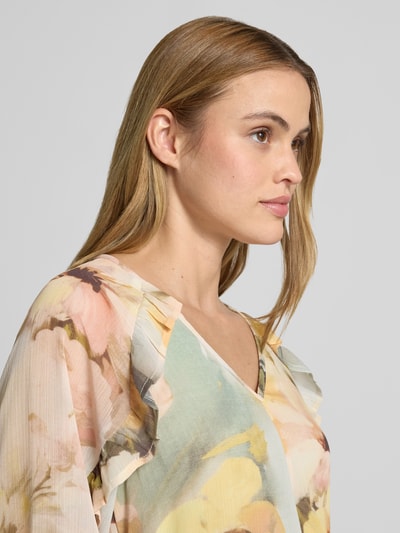 Frauenmodel trägt Midikleid mit V-Ausschnitt von Soyaconcept in floralen Pastellfarben, Rüschenbesatz, 3/4-Arm, Nahaufnahme Oberkörper, leicht taillierte Passform, Rückenlänge bei Größe S: 128 cm, Brustweite: 40 cm, Ärmellänge: 42 cm.