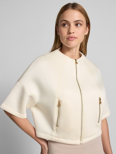 Frauenmodel trägt Jacke mit 1/2-Arm und Reißverschlusstaschen von Rinascimento aus cremefarbenem Viskose-Mix, Nahaufnahme Oberkörper.