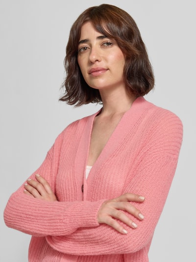 Frauenmodel trägt Strickjacke aus Alpaka-Mix mit V-Ausschnitt von Closed in Rosa, feine Stricktextur, Relaxed Fit, Nahaufnahme Oberkörper.
