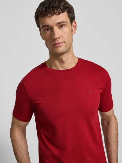 Männermodel trägt Regular Fit T-Shirt mit Logo-Stitching von Scotch & Soda in Rot aus reiner Baumwolle mit Rundhalsausschnitt, Nahaufnahme Oberkörper.
