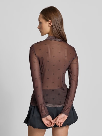 Modelka kobieca nosi Slim Fit Langarmshirt mit Allover-Muster Modell 'ERICA' od ONLY, czarne serca, materiał mesh, widok całej sylwetki z tyłu.