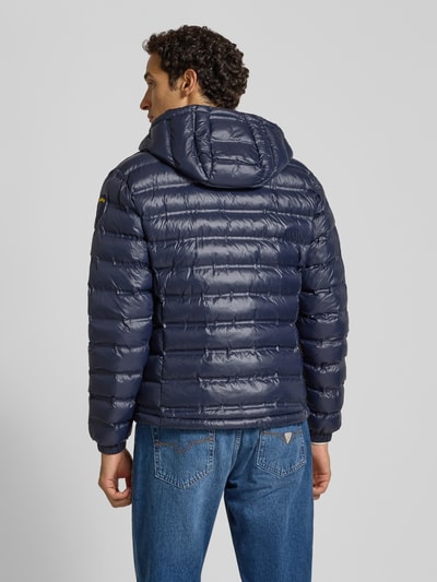 Männermodel trägt dunkelblaue Steppjacke mit Kapuze, Zweiwege-Reißverschluss, Label-Detail, Modell 'CHARLES' von Blauer USA, Ganzkörperansicht Rückansicht.