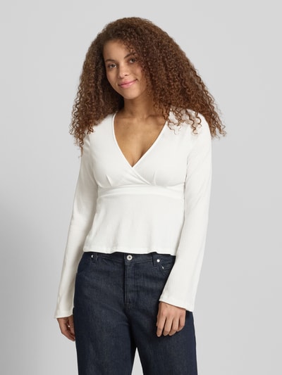 Frauenmodel trägt Regular Fit Langarmshirt in Wickel-Optik Modell 'PELLY' von Only mit Struktur-Muster, tiefem V-Ausschnitt, Trompetenärmeln, Bindeband, weiß, Ganzkörperansicht von vorne.