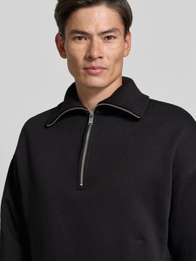 Männermodel trägt Regular Fit Sweatshirt aus Baumwoll-Mix mit Troyer-Kragen von DRYKORN, Logo-Stitching, Schwarz, Nahaufnahme Oberkörper.