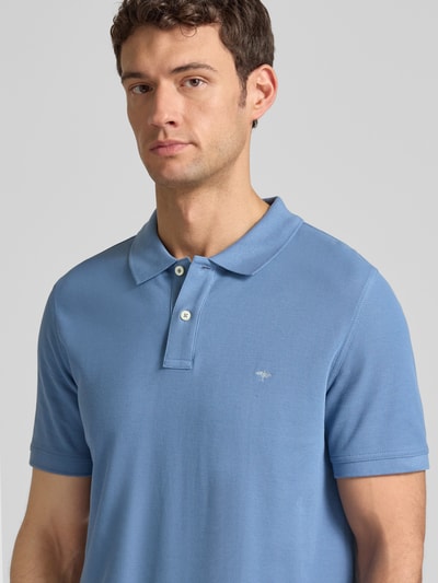 Männermodel trägt Regular Fit Poloshirt mit Label-Stitching van Fynch-Hatton in lichtblauw katoen, korte knoopsluiting, Nahaufnahme Oberkörper.