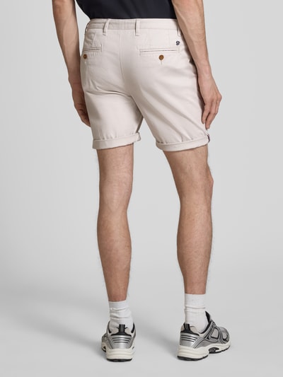 Männermodel trägt Regular Fit Shorts mit Münztasche von Superdry in Beige, Baumwoll-Mix, Gesäßtaschen, Ganzkörperansicht Rückansicht, krój regular fit, Szerokość w rozmiarze 32: 44 cm, długość nogawki wewnętrznej w rozmiarze 32: 20 cm