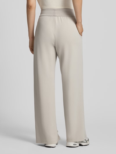 Vrouwenmodel draagt Straight Fit Sweatpants uit elastische viscosemix van Armani Exchange, lichte tint, labeldetail, pijpsplitten, elastische band, binnenbeenlengte maat S 77 cm, volledige lichaamsweergave achteraan.