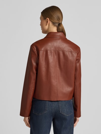 Frauenmodel trägt Jacke in Leder-Optik Modell 'SABI' von Mango, Regular-Fit, Reverskragen, Knopfleiste, Eingrifftaschen, Rückansicht.
