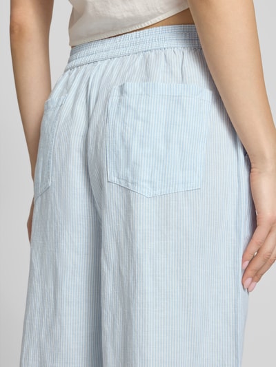 Frauenmodel trägt Weite HOSE aus Leinen-Mix mit Tunnelzug von Tommy Jeans, Two-Tone-Optik, Loose-Fit, Logo-Stitching, aufgesetzte Gesäßtaschen, seitliche Eingrifftaschen, Nahaufnahme Rückansicht.