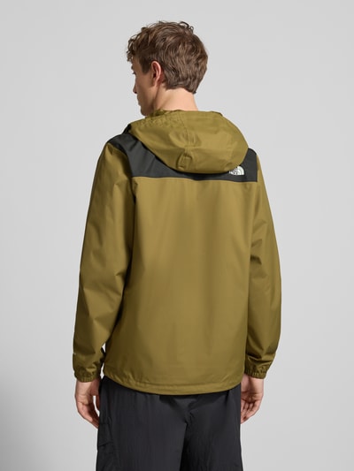 Męski model nosi Regular Fit Kurtka z nadrukiem z logo Model 'Antora' od The North Face, oliwkowa i czarna, wpuszczane kieszenie, kaptur z tunelem, elastyczne zakończenia rękawów, długość tyłu w rozmiarze M: 74 cm, szerokość ramion w rozmiarze M: 47 cm, szerokość klatki piersiowej w rozmiarze M: 58 cm, długość rękawów w rozmiarze M: 68 cm, widok całej sylwetki od tyłu
