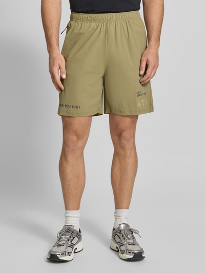 Männermodel trägt Shorts mit elastischem Bund Modell 'HALO AIR' von HALO in Olivgrün, Material-Mix mit Stretch, Regular Fit, Ganzkörperansicht von vorne.