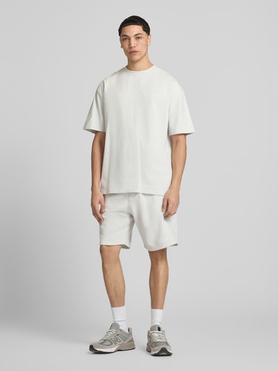 Mannenmodel draagt Oversized T-Shirt met Logo-Stitching van Pegador in gebroken wit, gemaakt van katoen, oversized fit, logostiksel, ronde hals, ruglengte maat M 73 cm, volledige vooraanzicht.