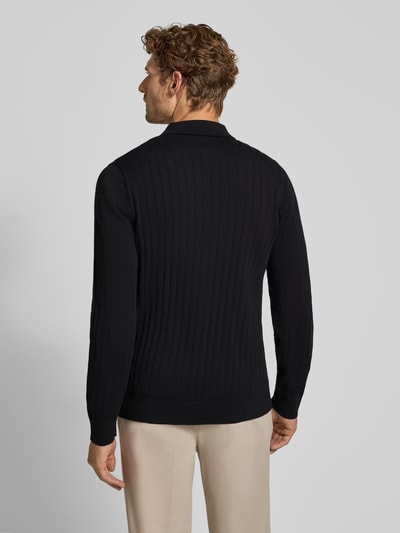 Männermodel trägt schwarzes Regular Fit Poloshirt aus reiner Baumwolle Modell 'TORINO' von Selected, strukturierte Oberfläche, Ganzkörperansicht Rückansicht. Herren Poloshirt von Selected.