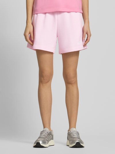 Vrouwenmodel draagt Shorts met elastische tailleband en trekkoord van adidas Sportswear, roze, regular fit, logo, katoenmix, voorkant geheel.