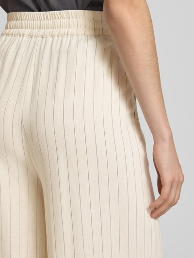 Frauenmodel trägt Loose Fit Pants mit Eingrifftaschen Modell 'tascha' von Gestuz im Viskose-Mix mit Leinen-Anteil, Creme mit dunklen Längsstreifen, ausgestellter Schnitt, elastischer Bund, Detailaufnahme Rückenpartie.