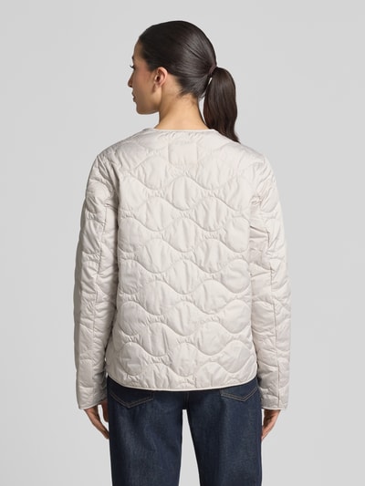 Vrouwenmodel draagt Steppjacke mit Rundhalsausschnitt van camel active in lichte kleur met doorgestikte naden, rechte fit, ruglengte 60 cm, schouderbreedte 43 cm, borstbreedte 53 cm, mouwlengte 64 cm, volledige drukknoopsluiting, geheel zicht van achteren.