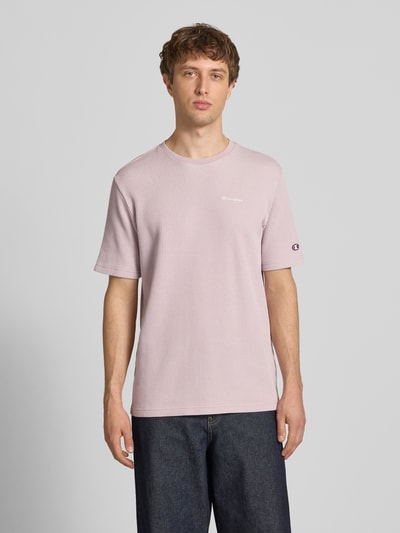 Männermodel trägt T-Shirt mit Strukturmuster und Label-Stitchings von CHAMPION in zartem Rosa, Baumwoll-Mix, Regular-Fit, Ganzkörperansicht von vorne. Rückenlänge bei Größe M: 68 cm.