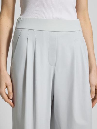Frauenmodel trägt Hose mit gelegten Falten Modell 'MAYLA 6/8 JOGG' von Raffaello Rossi in Hellgrau, elastischer Bund, Nahaufnahme Oberkörper. Material-Mix mit Stretch-Anteil, weites Bein.